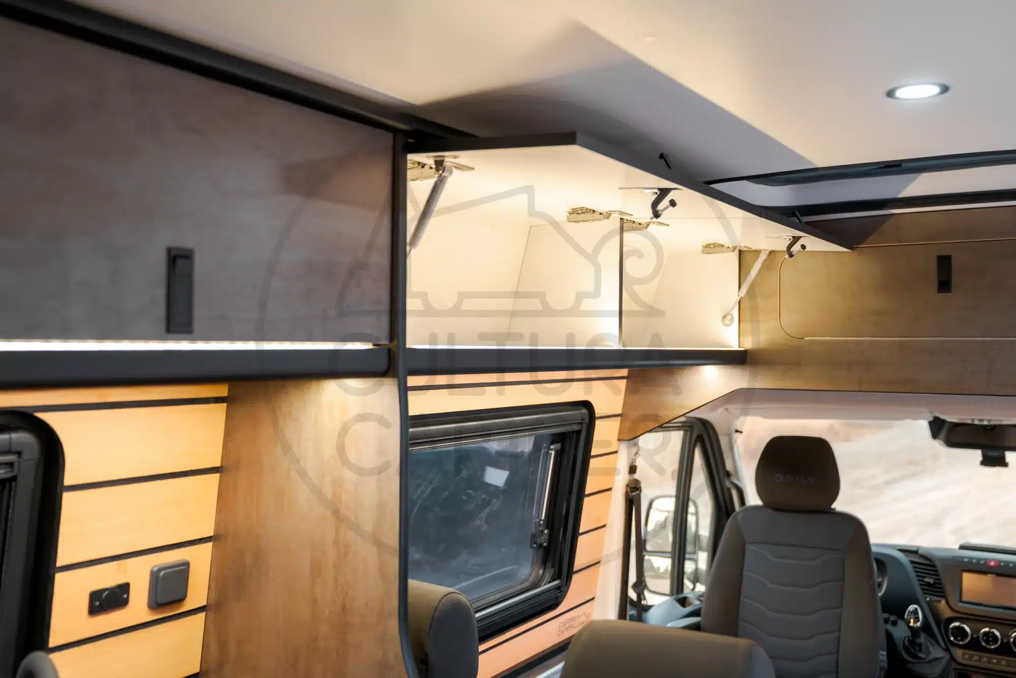 Innenansicht des Iveco Daily 4x4 Campers mit offenen Staufächern und Fahrerhaussitzen