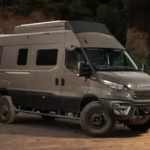 Iveco Daily 4x4 Camperfahrzeug auf sandigem Untergrund vor bewaldeter Kulisse