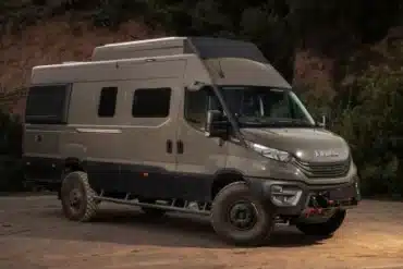 Iveco Daily 4x4 Camperfahrzeug auf sandigem Untergrund vor bewaldeter Kulisse