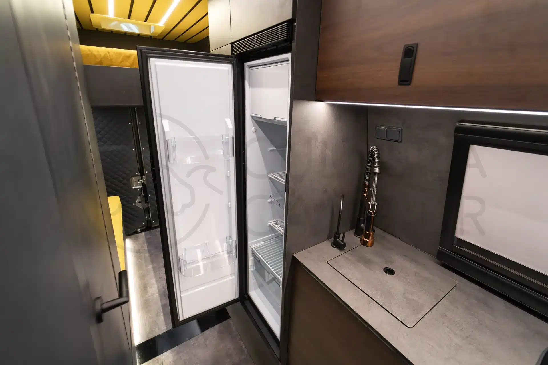 Küche mit Spüle und geöffnetem Kühlschrank im Ausbau eines Iveco Daily 4x4 Expeditionsfahrzeugs
