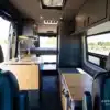 Innenansicht eines ausgebauten Mercedes Sprinter 170 High Roof Campervans mit Küchenzeile, Sitzbank und Bett.
