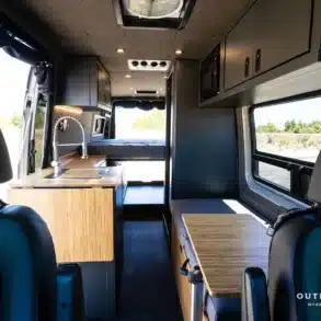 Innenansicht eines ausgebauten Mercedes Sprinter 170 High Roof Campervans mit Küchenzeile, Sitzbank und Bett.