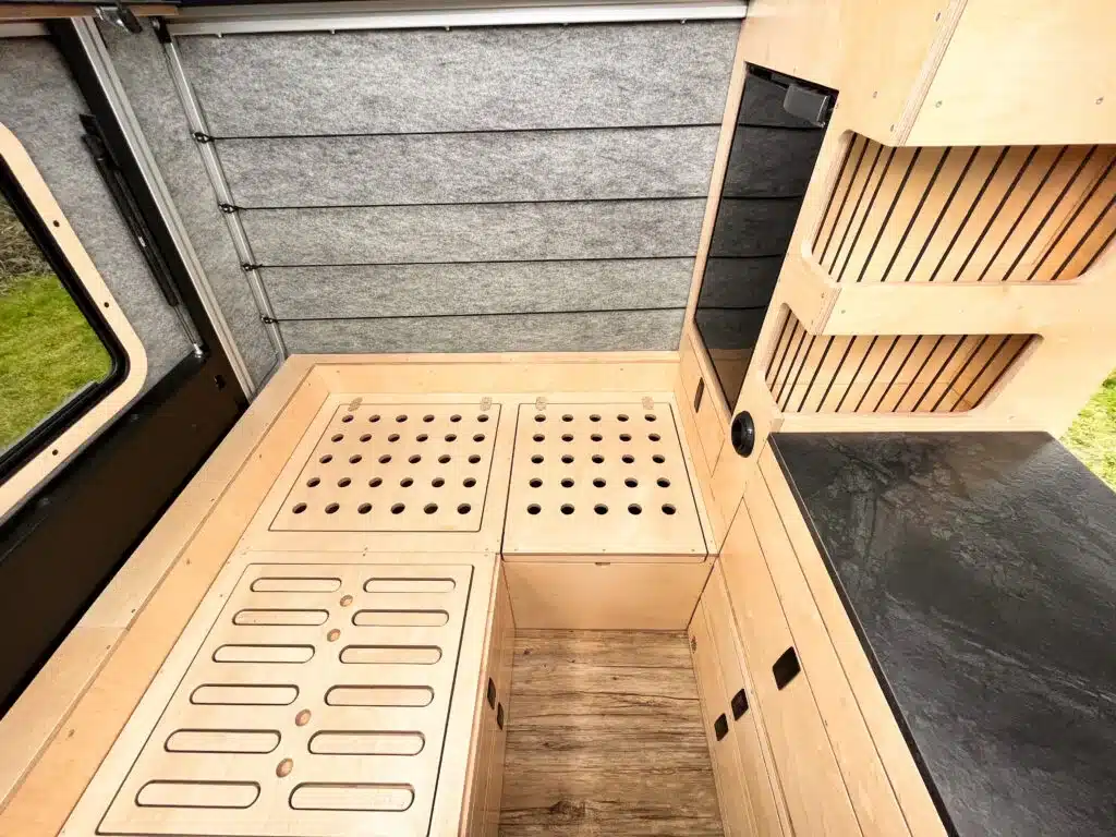 L-förmige Sitzgruppe und Stauraumlösungen im Innenausbau eines Defender 130 Pickup Campers