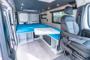 Innenraum eines Ram Promaster Low Roof mit Querbett, Sitzgruppe und Stauraum
