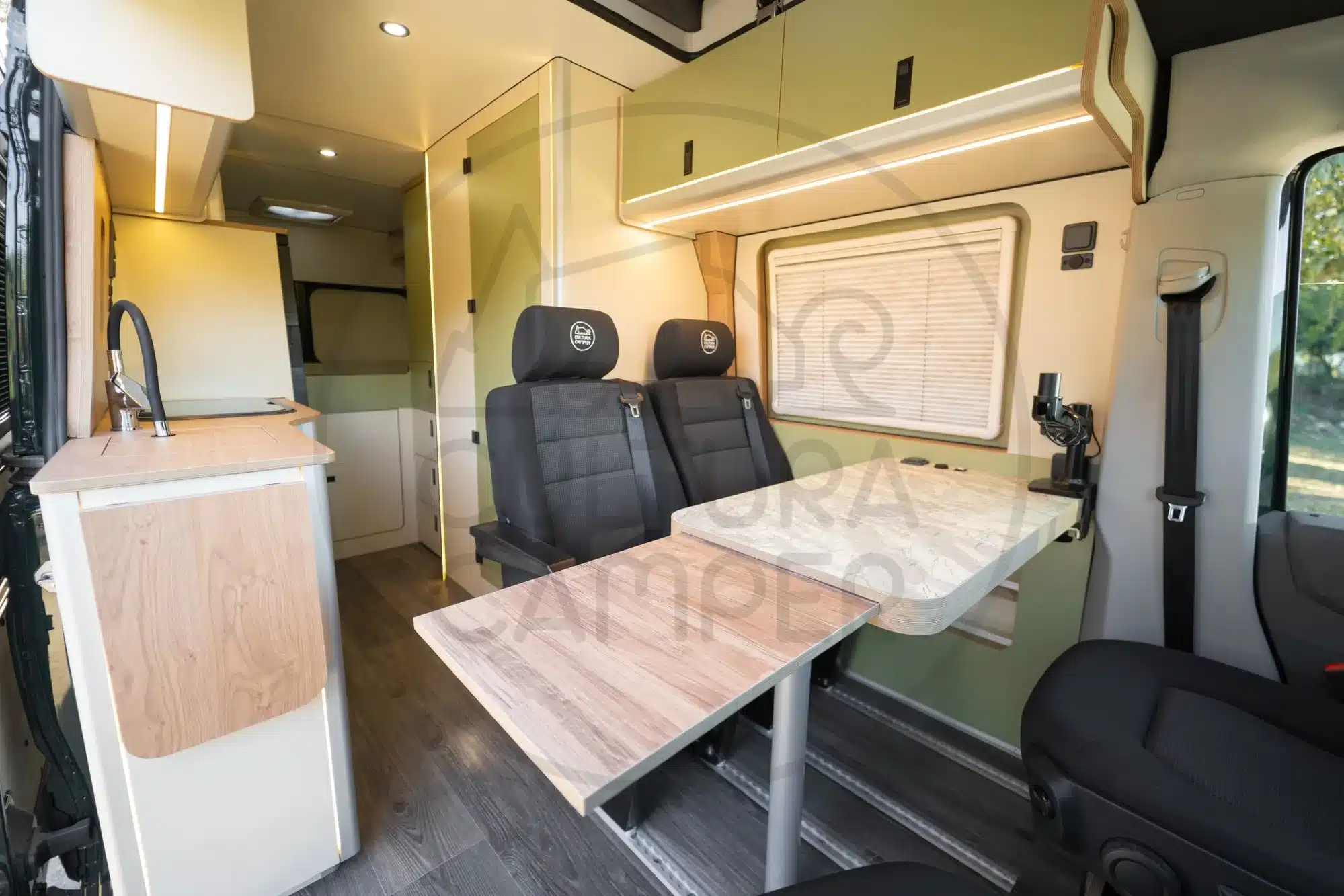 Moderner Innenraum eines MAN TGE 4x4 Compass on the Road Campers mit Küche, Sitzen und Tisch