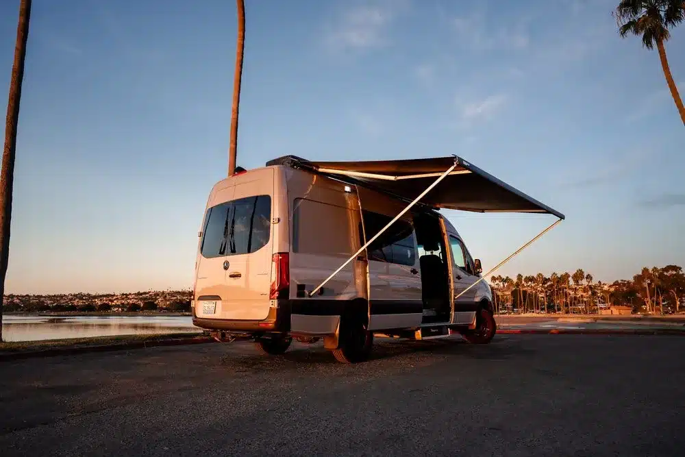 Barrierefreier Maverick-Campingbus mit geöffneter Seitenmarkise am Ufer – optimiert für Rollstuhlnutzer