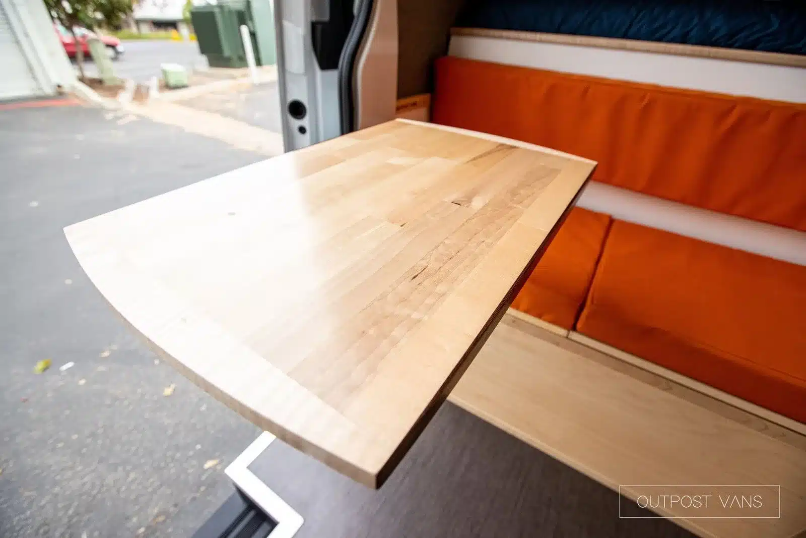 Ahorn-Arbeitsplatte im Campervan mit oranger Sitzbank im Hintergrund.