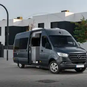 Mercedes Sprinter L4-H2 Campervan in Anthrazitgrau mit geöffneten Türen vor moderner Wohnanlage