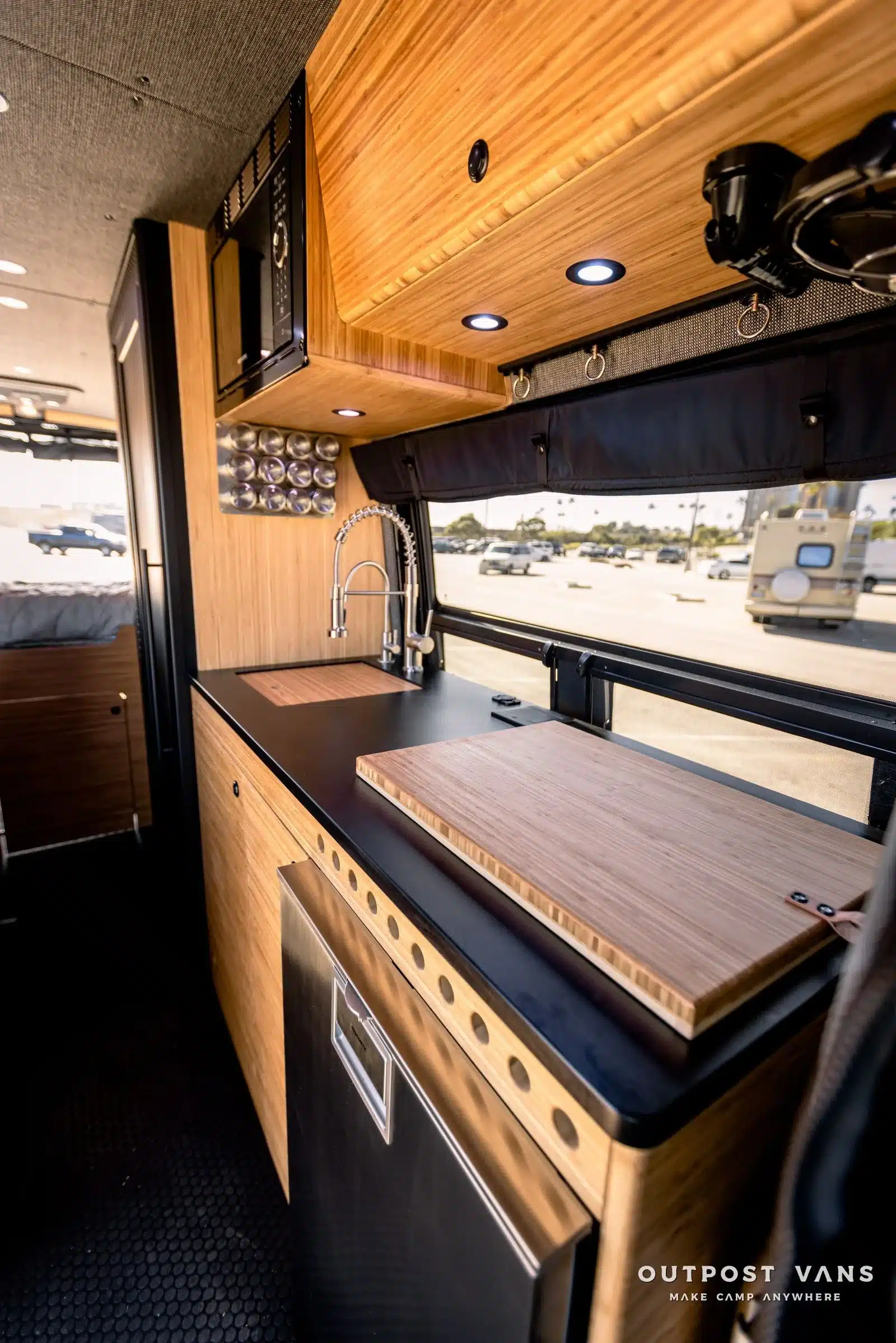 Innenraumansicht der modernen Küche im Mercedes Sprinter Mamba Van mit Arbeitsplatte, Spüle, Mikrowelle und Fenster.