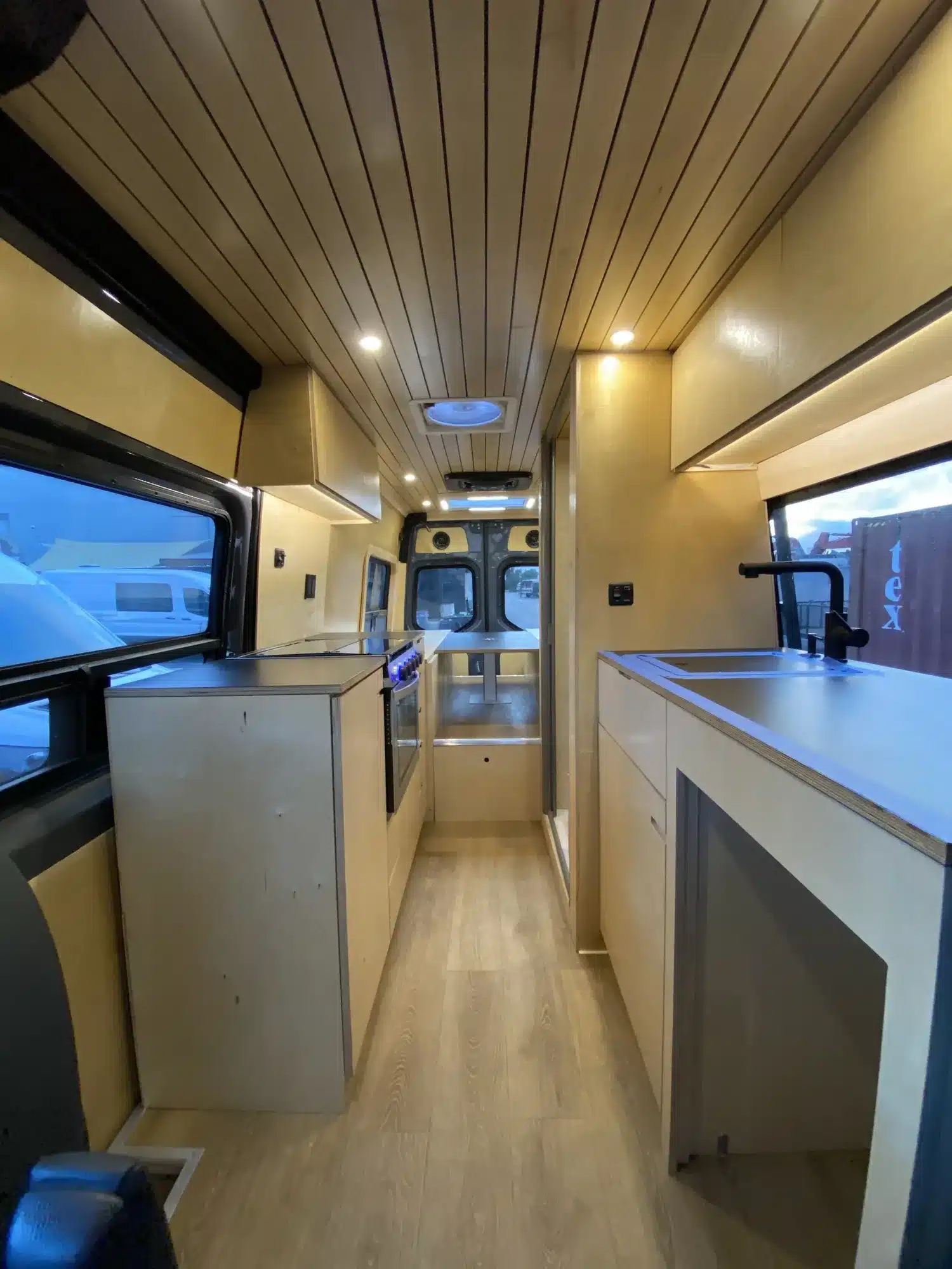 Heller Innenraum eines Moose-Campervans mit viel Birkenholz, Küche, Spüle und Stauraum