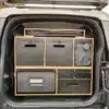 Modulare Campingbox im Kofferraum eines Land Rover New Defender mit verschiedenen Fächern und Kühlbox.