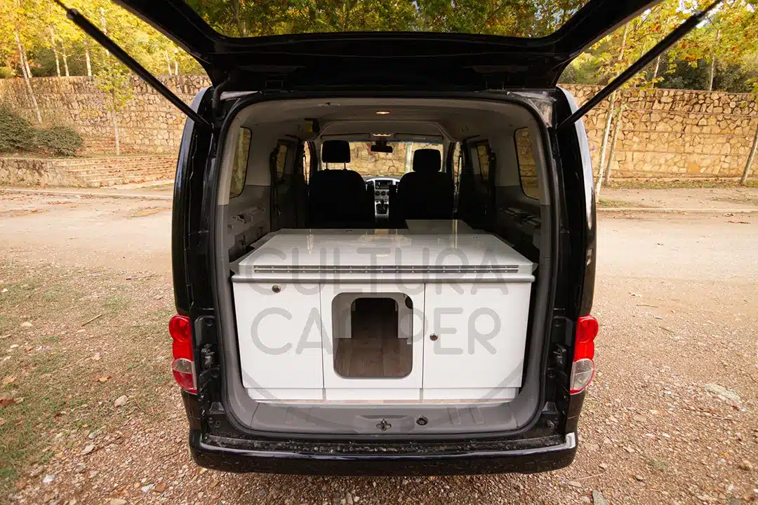 Heckansicht eines ausgebauten Nissan NV200 mit geöffneter Heckklappe und eingebautem Campingmodul
