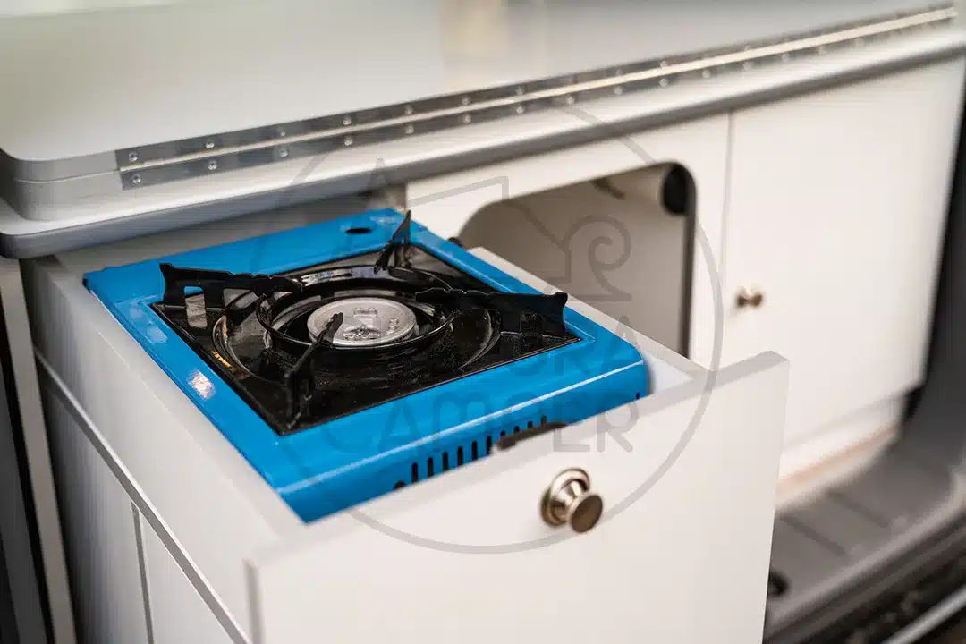 Campingtauglicher blauer Gaskocher im ausziehbaren Küchenelement eines umgebauten Nissan NV200 Campervans