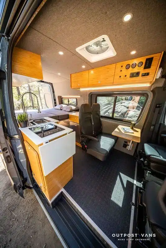 Innenraum des Outpost Vans CRAG mit Küchenzeile, Sitzbereich und festem Bett auf Mercedes Sprinter-Basis