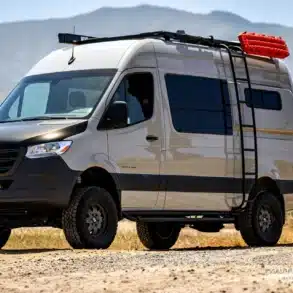 DUNE Campervan, ausgebauter Mercedes Sprinter 4x4 Offroad mit Dachträger, Leiter und Expeditionszubehör auf Schotterpiste.