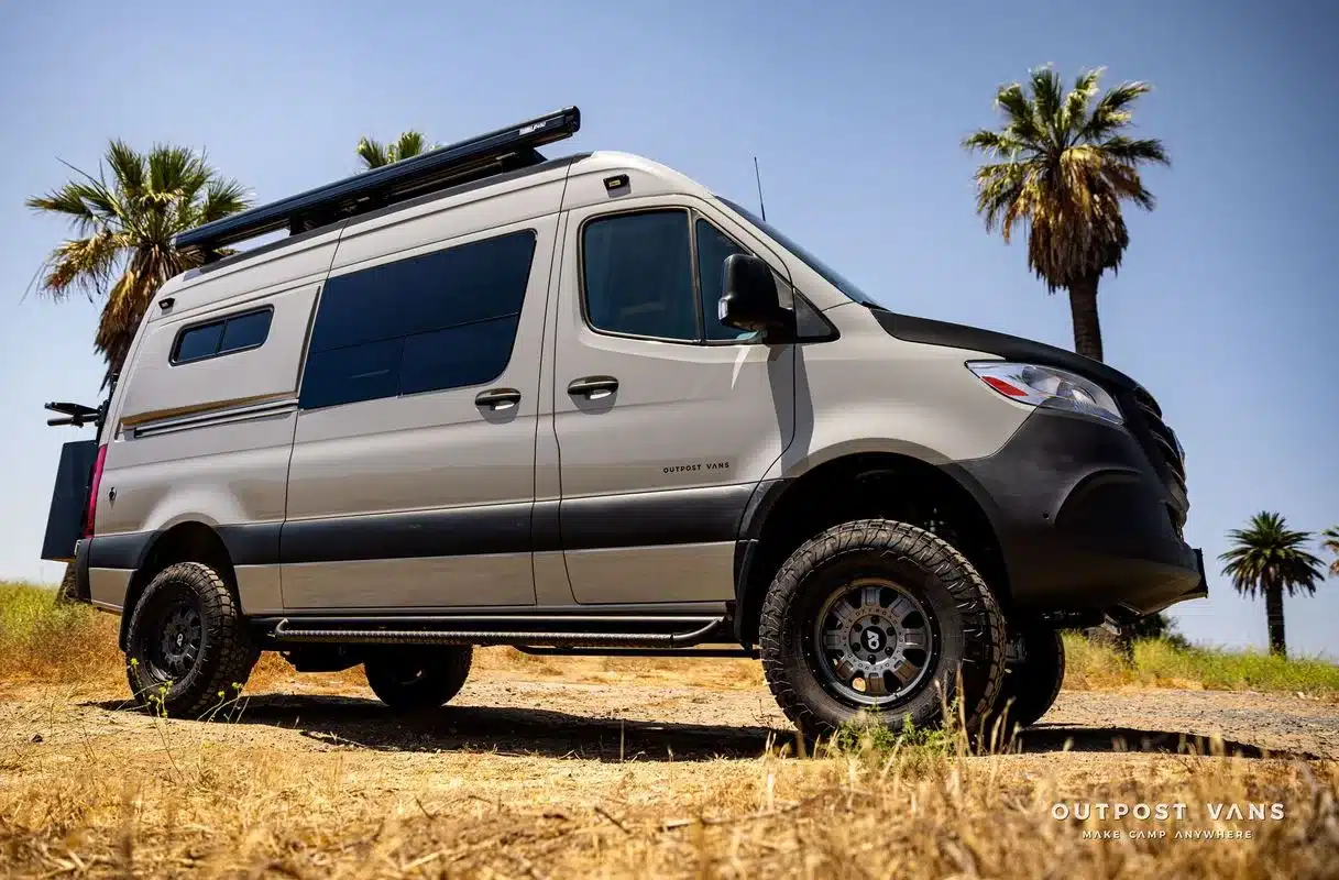Seitenansicht des DUNE Campervans, ausgebaut auf einem Mercedes Sprinter mit Allradantrieb und Offroad-Zubehör, geparkt in sonniger Landschaft.