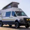 Seitenansicht des Outpost Vans Günter, ein ausgebauter Offroad-Campervan auf Mercedes Sprinter Chassis mit Aufstelldach, robusten Reifen und Zubehör für Expeditionen.