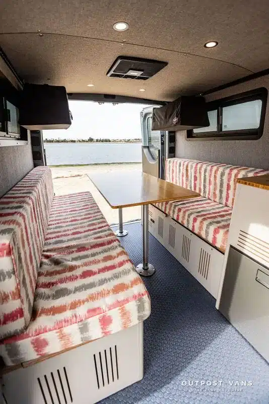 Dinette-Sitzgruppe im Ausbaubereich eines Outpost Vans Jasper mit Blick nach draußen ans Wasser