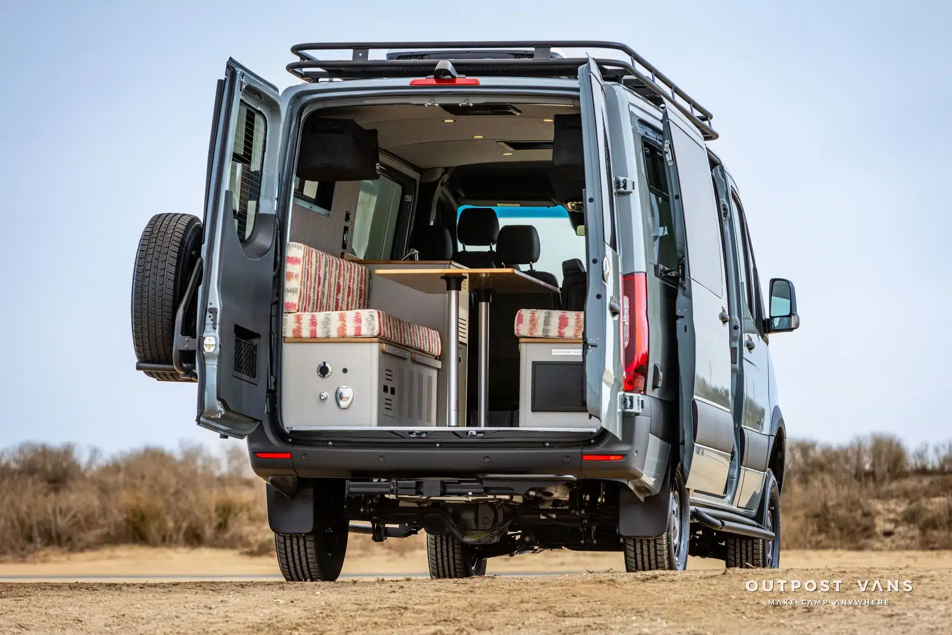 Outpost Vans Jasper Campervan mit Blick durch die geöffnete Hecktür auf die Dinette und den Innenausbau.
