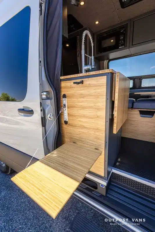 Klappbarer Außentisch und Küchenzeile mit Spüle aus Bambus im Outpost Vans Sprinter 170 Innenausbau.
