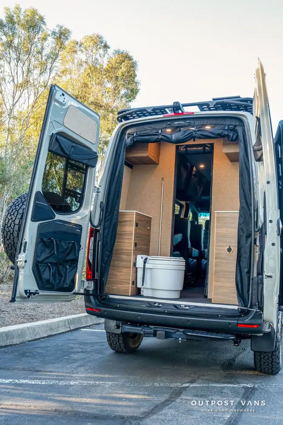 Geöffnete Hecktüren des Outpost Vans LOBO zeigen das fest integrierte Bad, Stauraum und robuste Ausstattung.