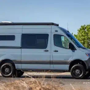 Seitliche Ansicht eines Outpost Vans Sol Campervans auf Mercedes-Benz Sprinter 144 mit Allradantrieb, geparkt in der Natur.