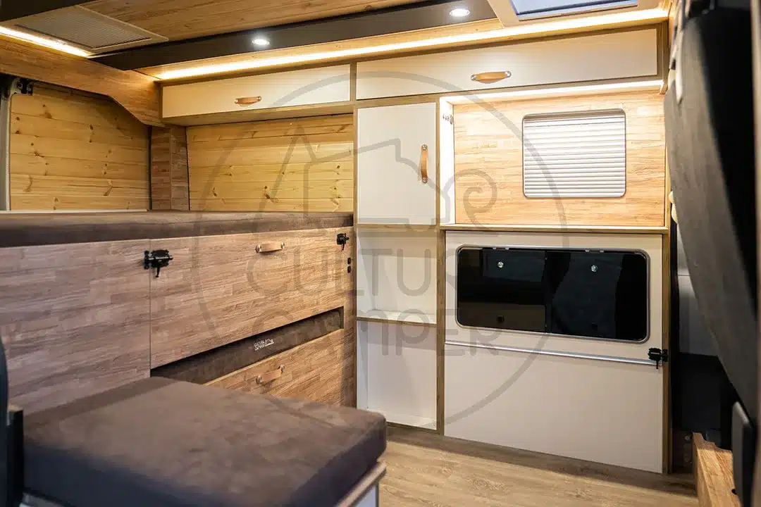 Innenansicht des Peugeot Boxer L1H1 Van-Cabaña mit klappbarer Küchenzeile, Stauraum und Schlafbereich.