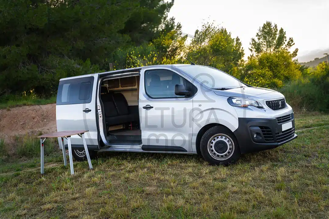 Peugeot Expert Van mit offenem Seiteneingang und Campingtisch auf einer Wiese