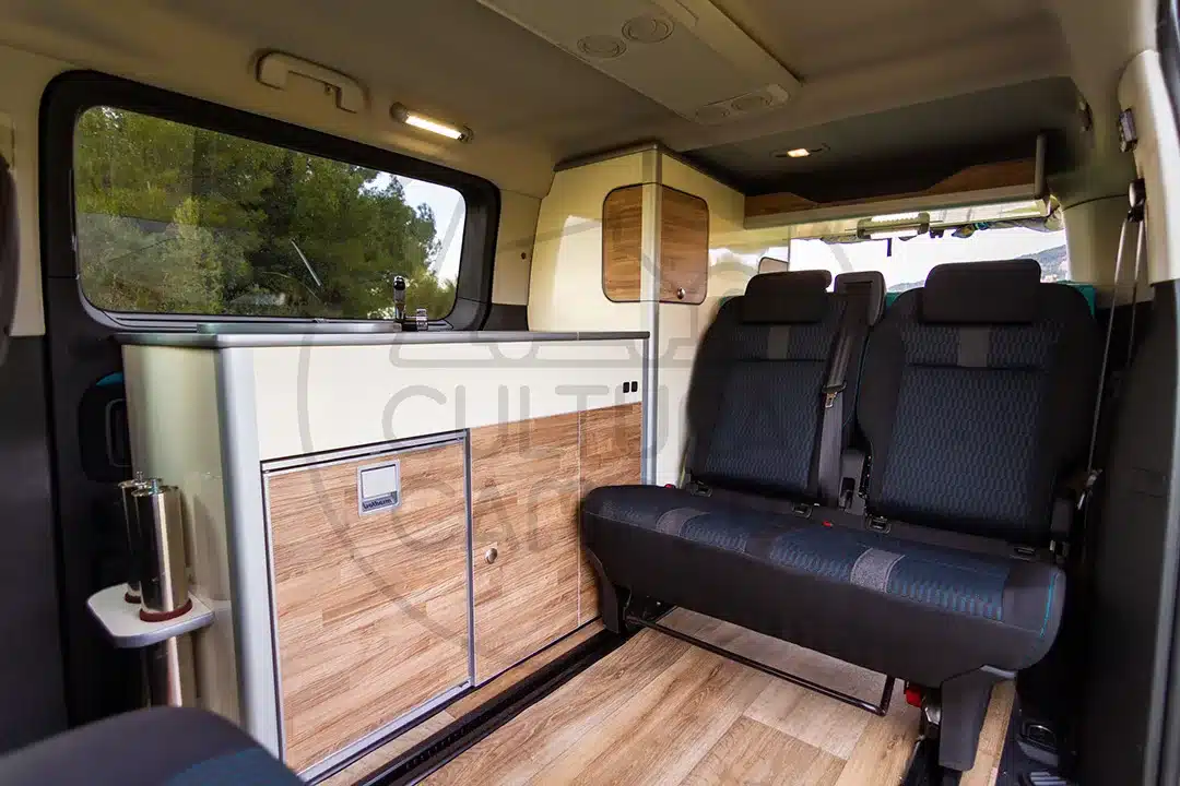 Innenansicht eines Peugeot Traveller Campers mit Sitzbank und integrierter Küchenzeile in Holzoptik