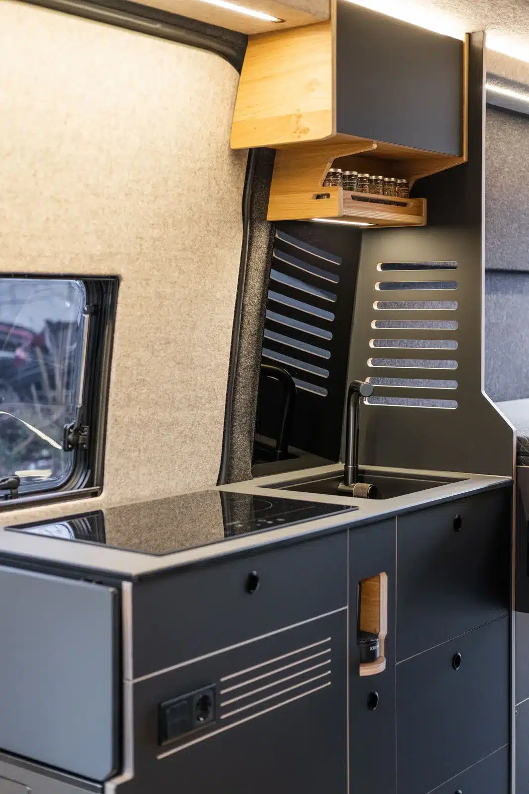 Innenansicht der Campervan-Küche mit Induktionskochfeld, Spüle und Oberschrank im Mercedes-Benz Sprinter 'Project Hispaniola'