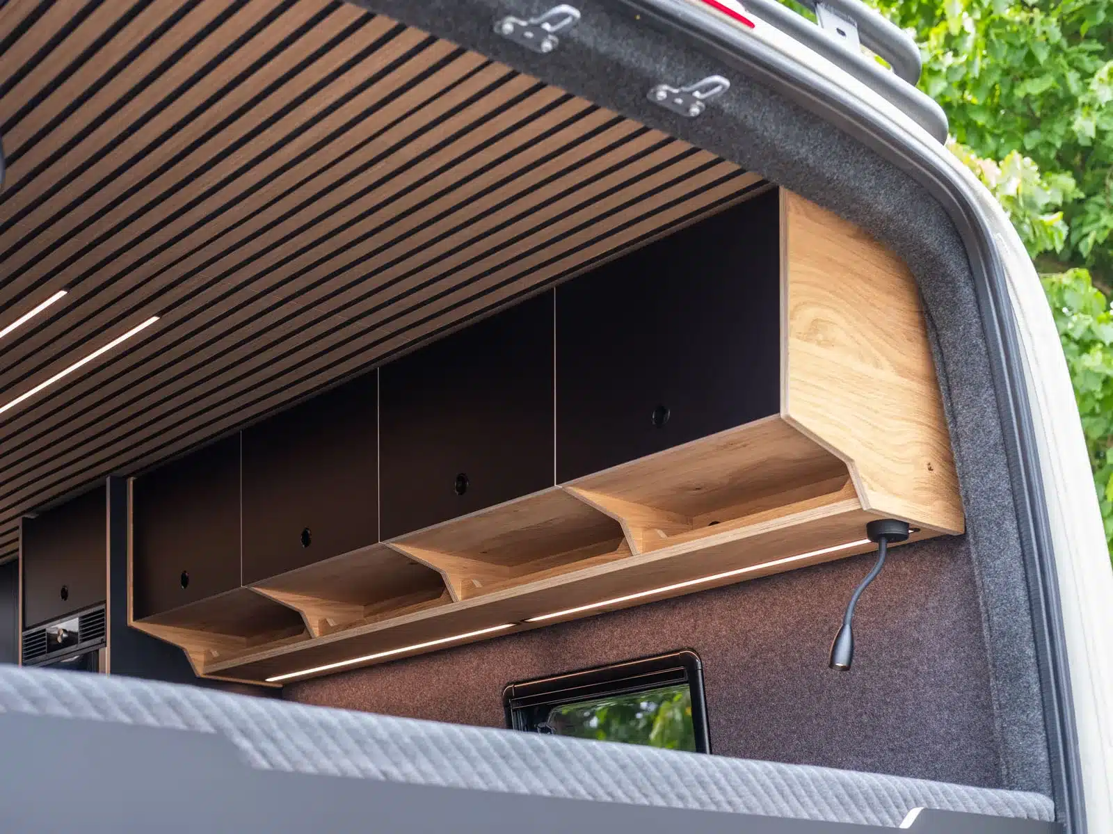 Moderner Stauraum mit Hängeschränken und Holzdecke im Innenraum eines Mercedes Sprinter Campers