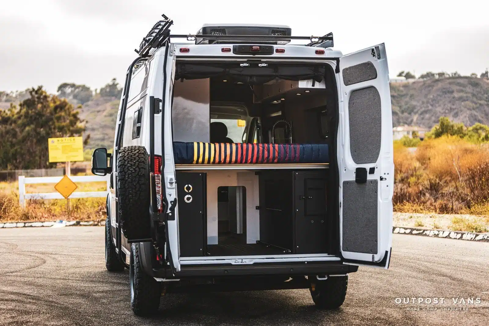 Blick durch die geöffneten Hecktüren eines Ram Promaster Altitude Campervans mit ausgebautem Wohn- und Stauraum