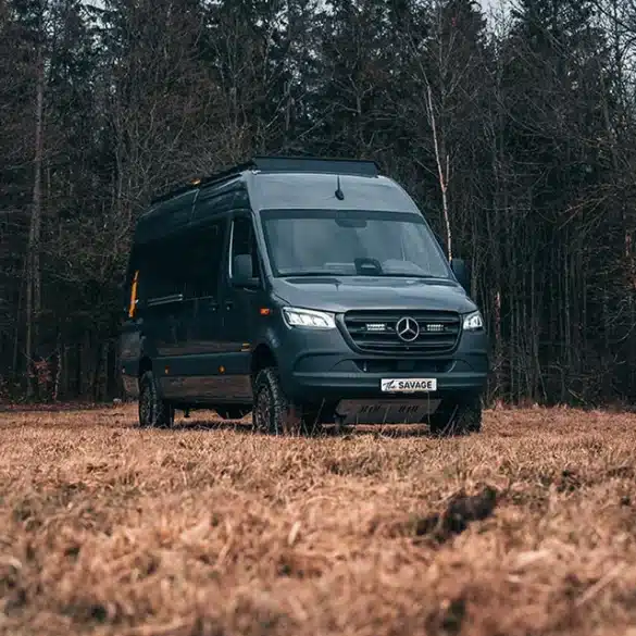 Rhön Camp THE SAVAGE Campervan auf Mercedes Sprinter Basis steht auf einer Lichtung vor Bäumen
