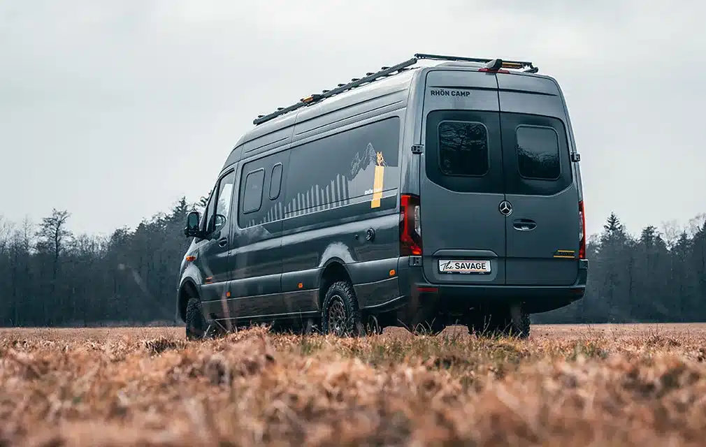 Campervan Rhön Camp THE SAVAGE auf Mercedes Sprinter-Basis auf einem Feld mit bewölktem Himmel.