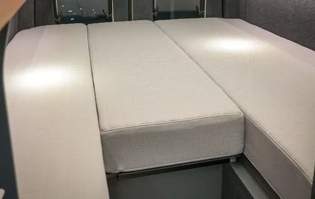 Komfortables Längsbett mit heller Matratze im Camper Rhön Camp THE SAVAGE, Blick auf den Schlafbereich
