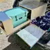 Toyota Highlander mit Camper-Ausbau, ausziehbare Yeti-Kühlbox-Schublade und Tisch, Einzel-Schlafplatz im Kofferraum.
