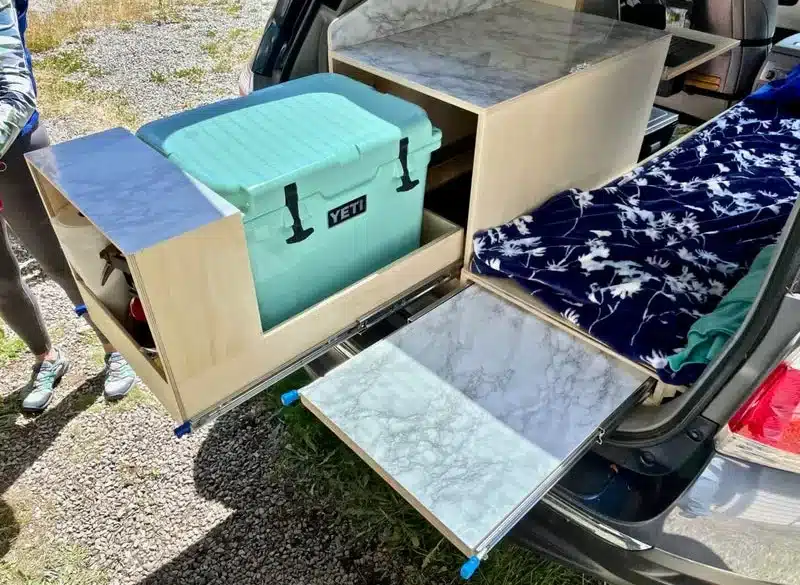 Toyota Highlander mit Camper-Ausbau, ausziehbare Yeti-Kühlbox-Schublade und Tisch, Einzel-Schlafplatz im Kofferraum.