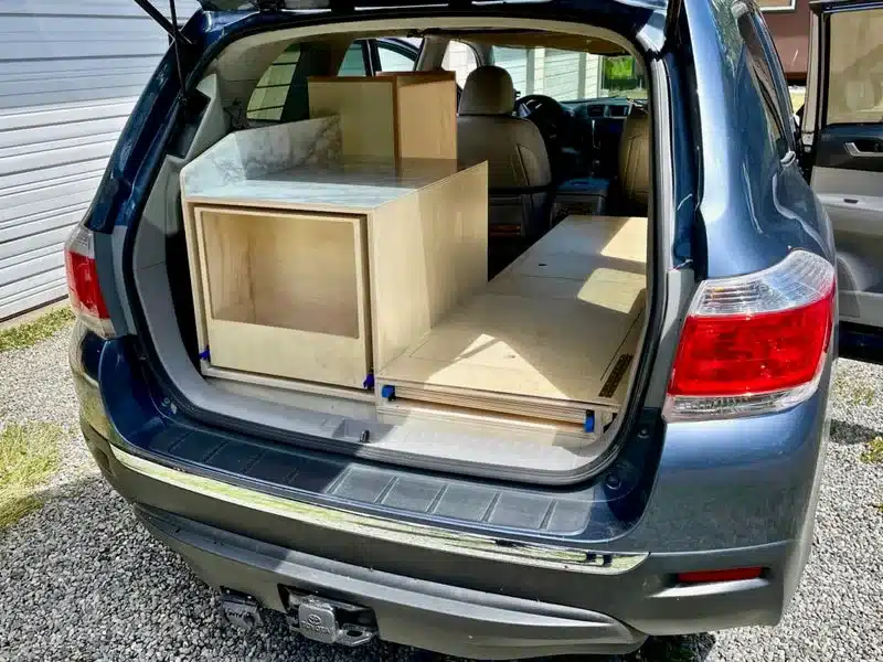 Maßgeschneiderter Camper-Ausbau mit Stauraum und Schlafplattform im Kofferraum eines Toyota Highlander 2013.