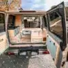 Innenausbau eines Toyota Land Cruiser 76 als Mini-Camper mit flexibler Sitz- und Liegefläche, Stauraum und Küchenmodulen, bei geöffneter Heckklappe