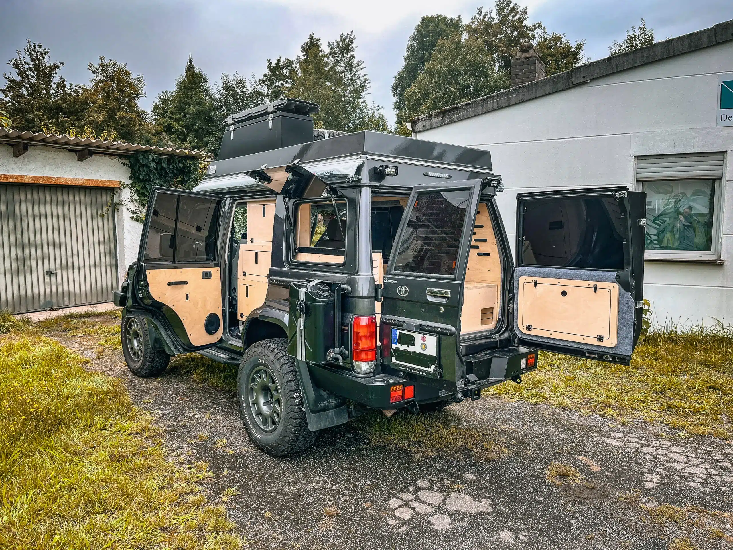 Toyota Land Cruiser GRJ 76 Camper mit geöffneten Türen, Aufstelldach und Stauraum im Außenbereich, ideal für Offroad und Vanlife.