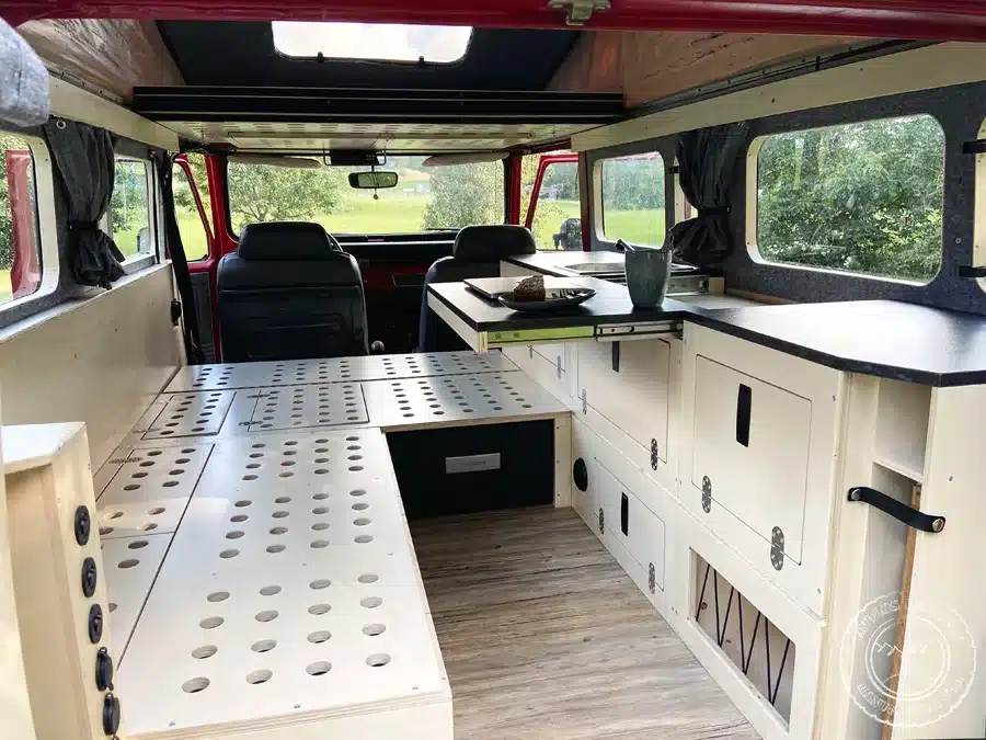 Innenraum eines ausgebauten Toyota Land Cruiser BJ45 mit Holzmodulen, Schlafbereich und Küchenzeile als Camper.