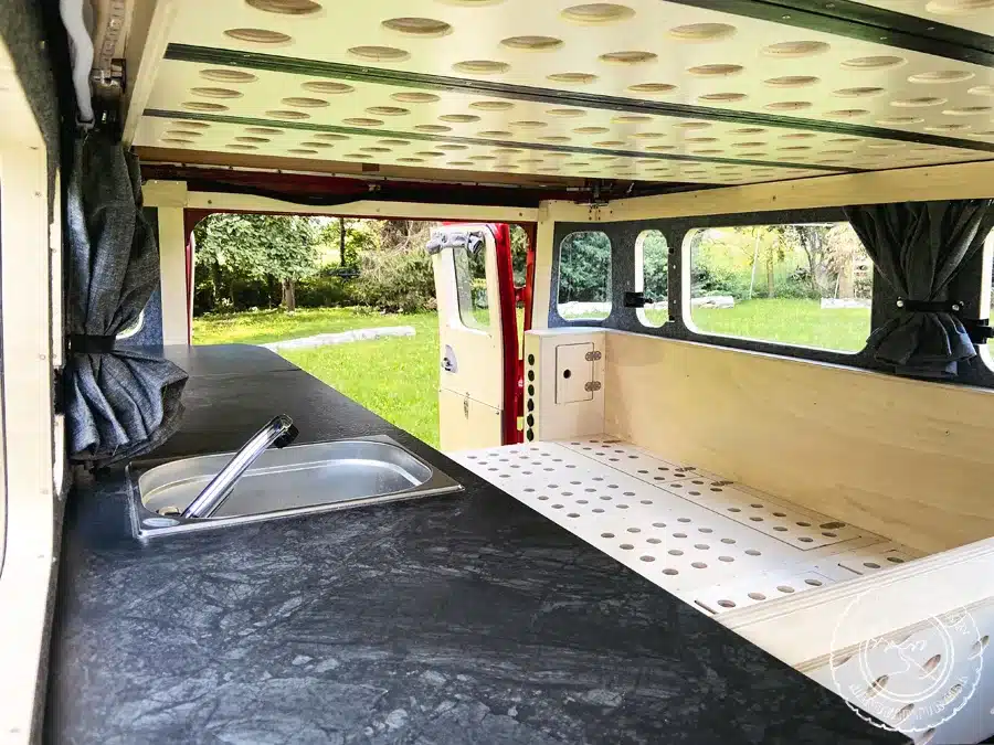 Innenansicht des ausgebauten Toyota Land Cruiser BJ45 mit Küchenzeile, Holzverkleidung und Hubdach-Bett