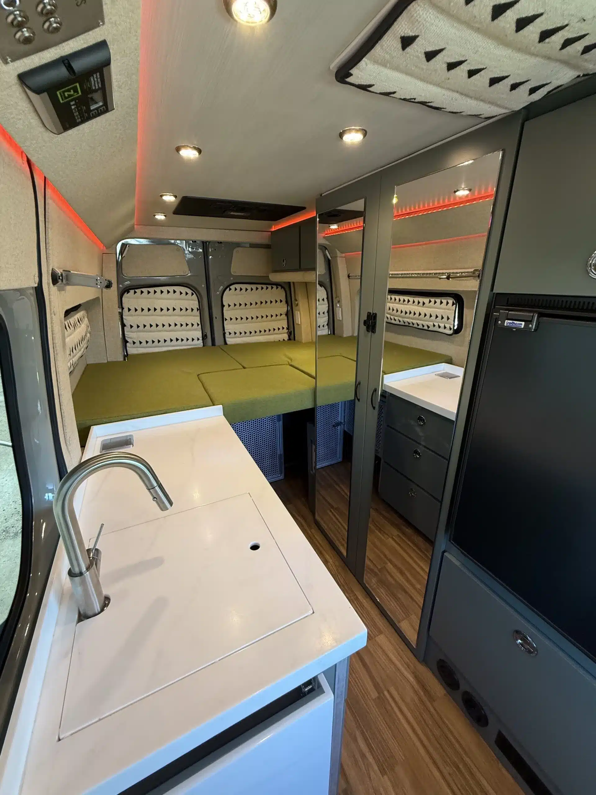 Innenraum eines Trail-Hob Adventure-Vans auf Sprinter 144 AWD Basis mit Plattformbett, Küchenzeile, Bad und Stauraum