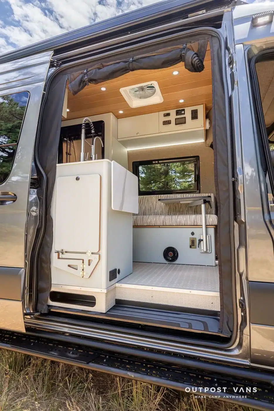 Innenansicht eines Offroad-Campervans vom Eingang aus mit Küchenschrank, Edelstahlspüle und Sitzbank.
