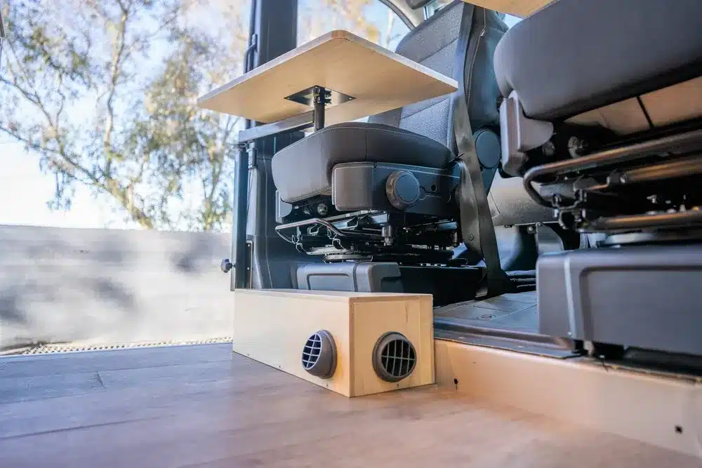 Blick auf ein drehbares Fahrersitzmodul mit Holz-Arbeitsplatte und integriertem Heizmodul im Kastenwagen-Ausbau Avalon