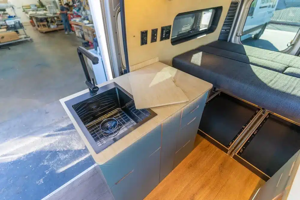 Modulares Küchensystem und Futon-Bett im Innenraum des Avalon-Kastenwagens von Vamonos Vans