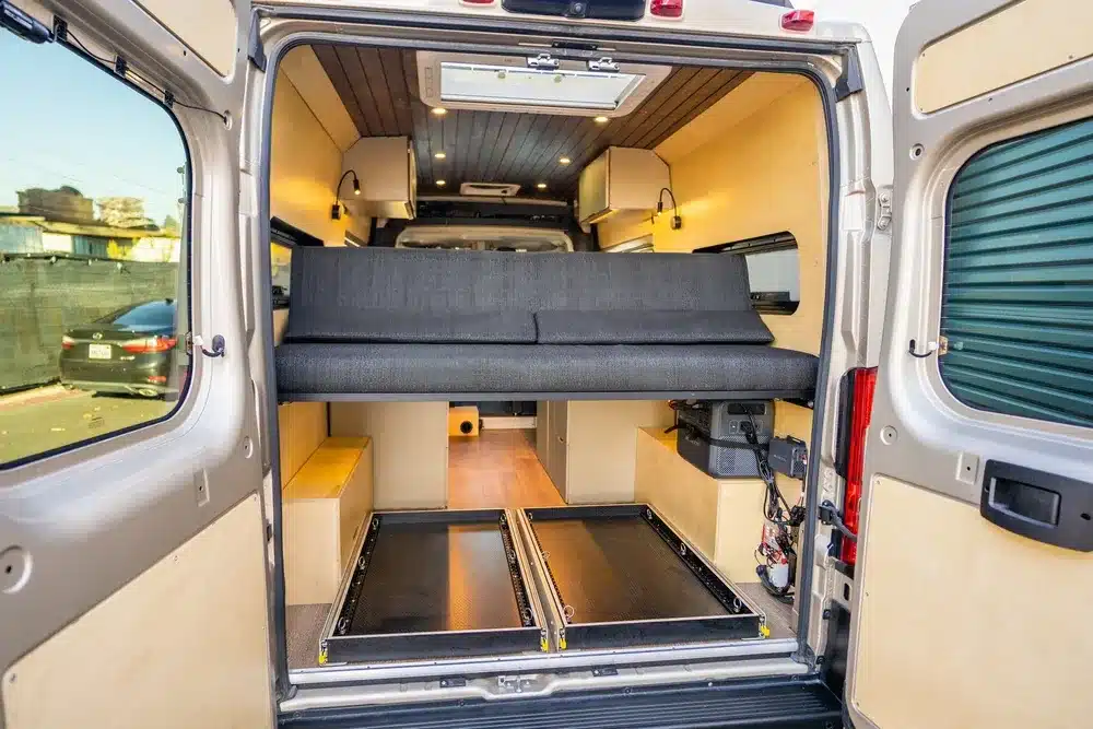 Blick in den Innenraum eines Avalon Campervans mit aluminiumgerahmtem Futon-Bett und Stauraum