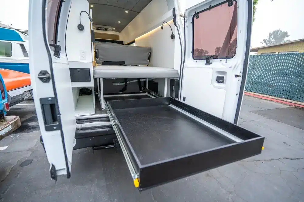 Rückansicht des Vamonos Vans Turq mit ausziehbarer Staubox und modularer Camping-Innenausstattung.