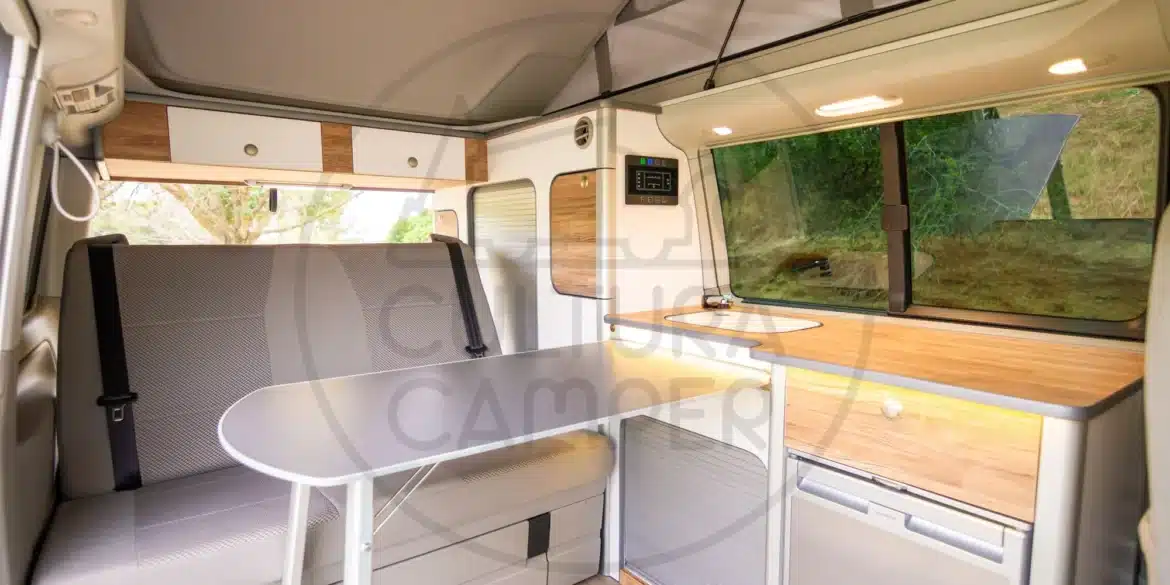 Innenansicht des VW T6 California mit maßgeschneidertem Möbelkonzept, Küchenzeile, Sitzbank und heller, moderner Gestaltung
