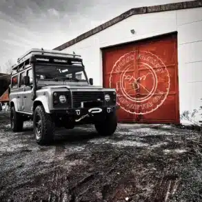 Land Rover Defender 110 mit Dachzelt und Offroad-Umbau vor der Werkstatt Endlos Freistehen Manufaktur